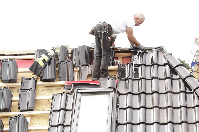 Roofers tiling around a dormer window